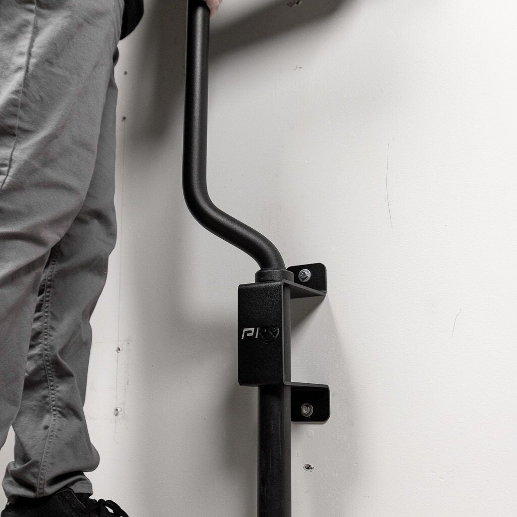 Specialty barbell stored vertically on the PRx wall mount in a home gym