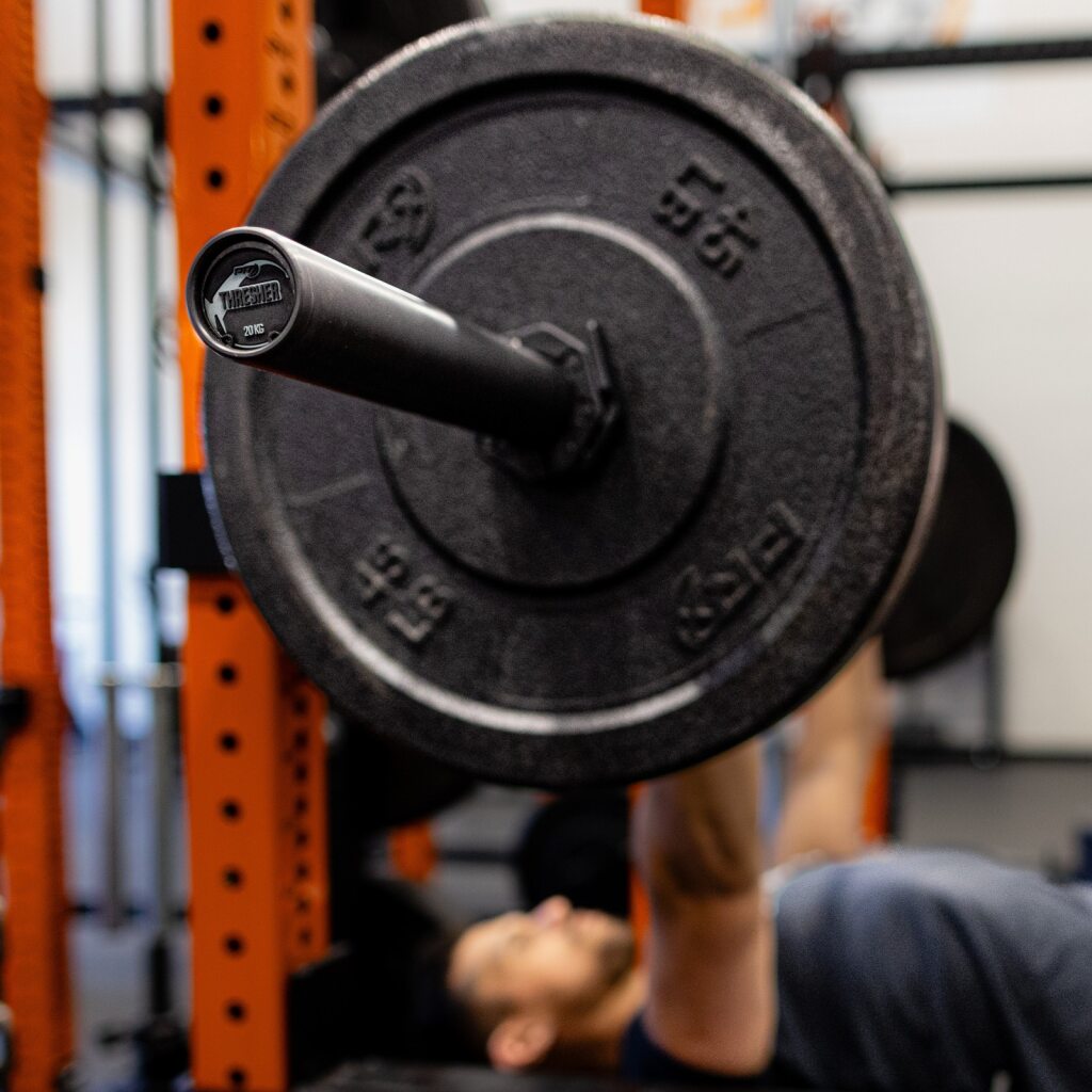 PRx Thresher Barbell loaded with bumper plates in a rack